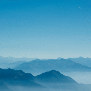 Paesaggio di montagne sfumate nel blu sotto un cielo azzurro limpido, simbolo di calma, introspezione e spiritualità.